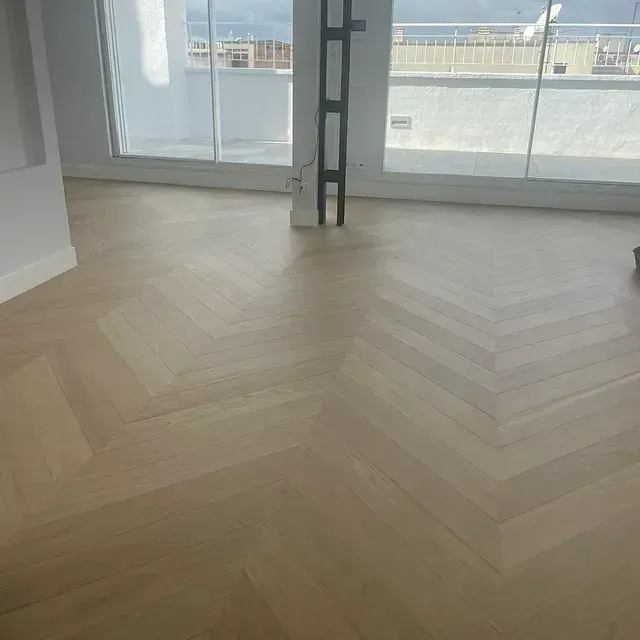 Una habitación con suelo de madera y una gran ventana.