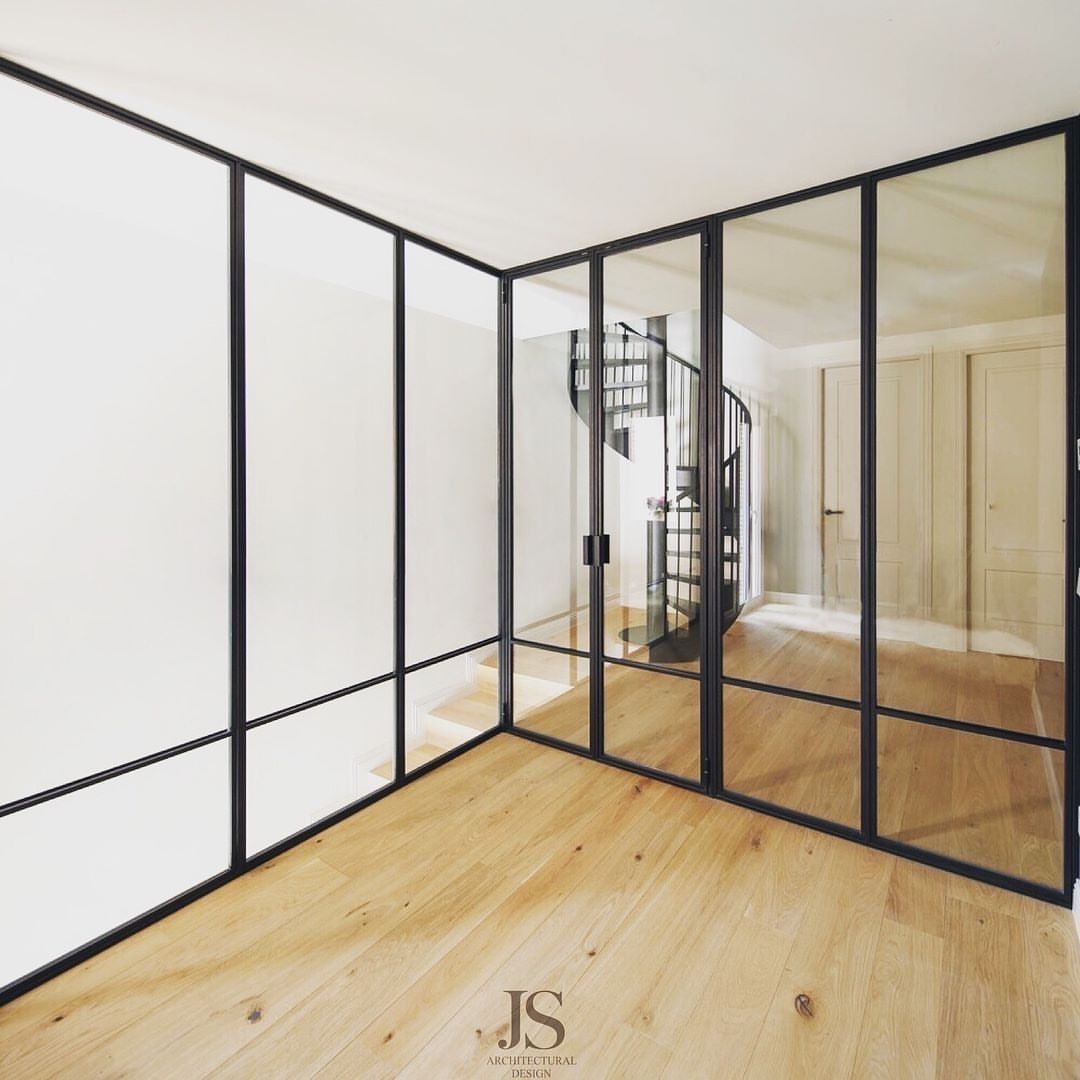 Una habitación con una escalera de caracol detrás de una pared de cristal.