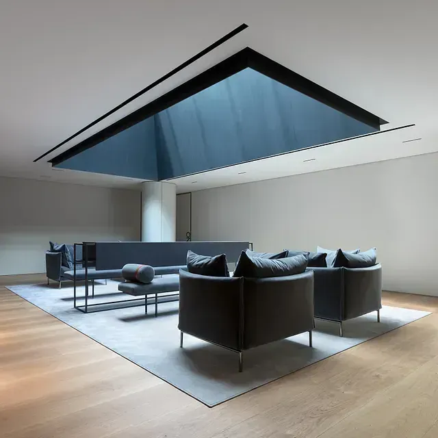 Una sala de estar con un sofá y sillas bajo un tragaluz azul.