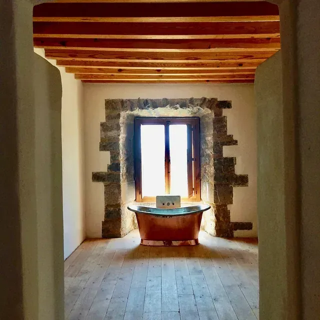 Un baño con una bañera de cobre frente a una ventana.
