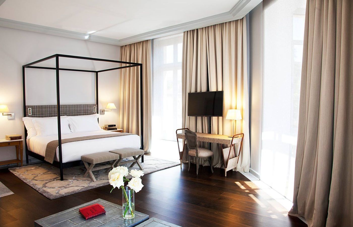 Una habitación de hotel con una cama con dosel y un escritorio.