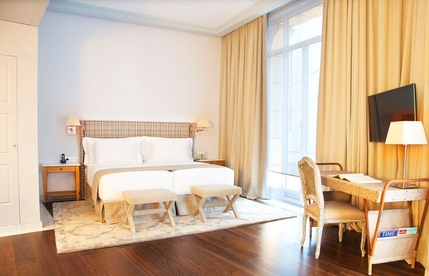 Una habitación de hotel con dos camas, un escritorio, sillas y un televisor.