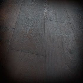 Un primer plano de un piso de madera oscura en una habitación oscura.