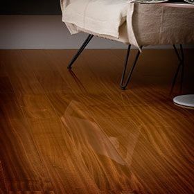 Un piso de madera con una silla y una mesa al fondo.