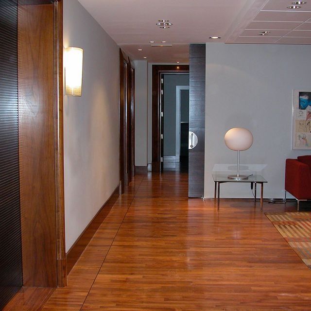 Un pasillo con pisos de madera y una lámpara sobre una mesa.