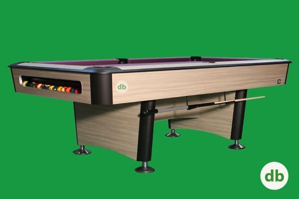 Una mesa de billar con acabado de veta de madera clara, detalles negros y fieltro morado. Se destaca sobre un fondo verde.