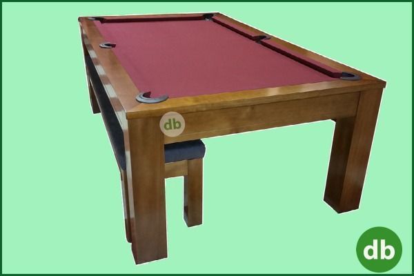 Mesa de billar de madera con fieltro rojo, en una habitación con fondo verde. Un taburete es parcialmente visible.
