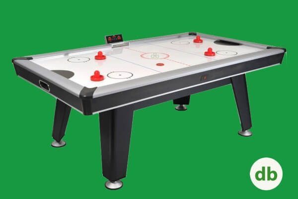 Mesa de air hockey con discos y delanteros rojos, marco negro y plateado, sobre un fondo verde.