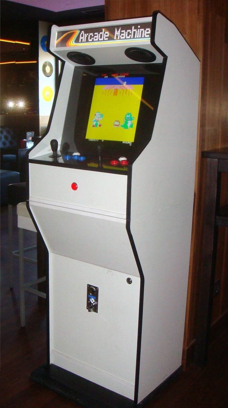Máquina arcade blanca con una pantalla que muestra un juego pixelado amarillo y verde. La máquina tiene un joystick, botones y un altavoz sobre la pantalla.