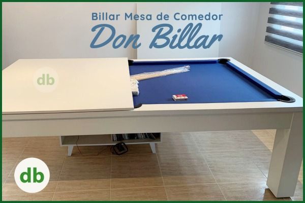 Mesa de comedor/billar blanca combinada con fieltro azul, con el tablero parcialmente desmontado. El logotipo 