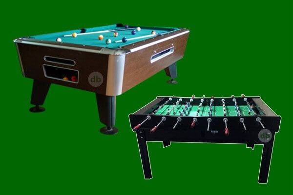 Mesa de billar y futbolín sobre fondo verde; la mesa de billar es marrón con una superficie de fieltro verde y bolas, y la mesa de futbolín es negra.