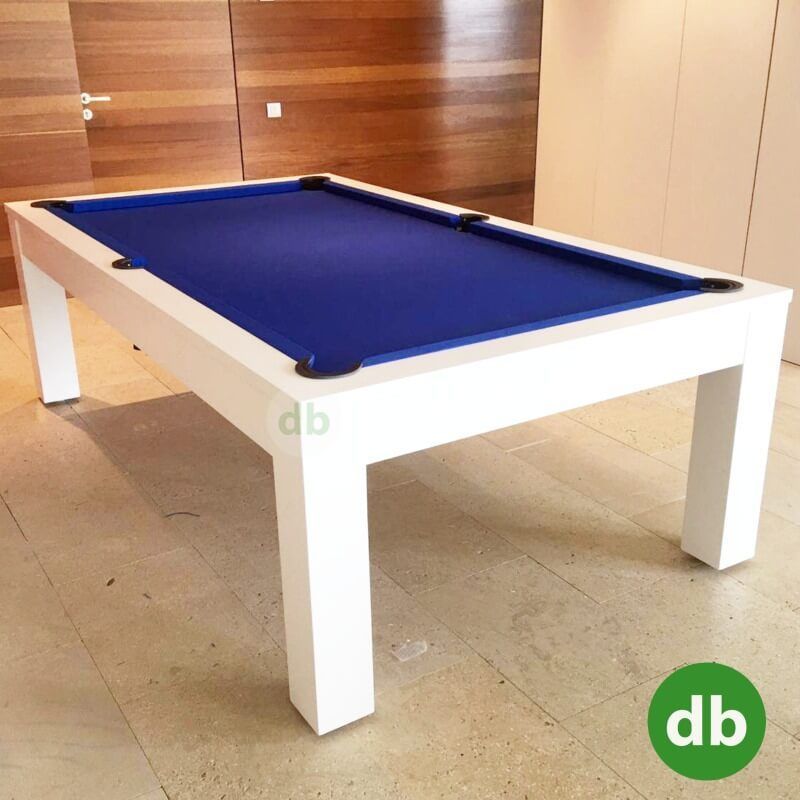 Mesa de billar moderna blanca con fieltro azul en una habitación con paredes y suelo de colores claros.