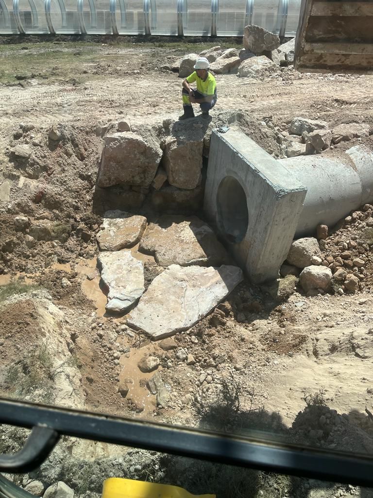 Un hombre está sentado en una roca al lado de una tubería en la tierra.