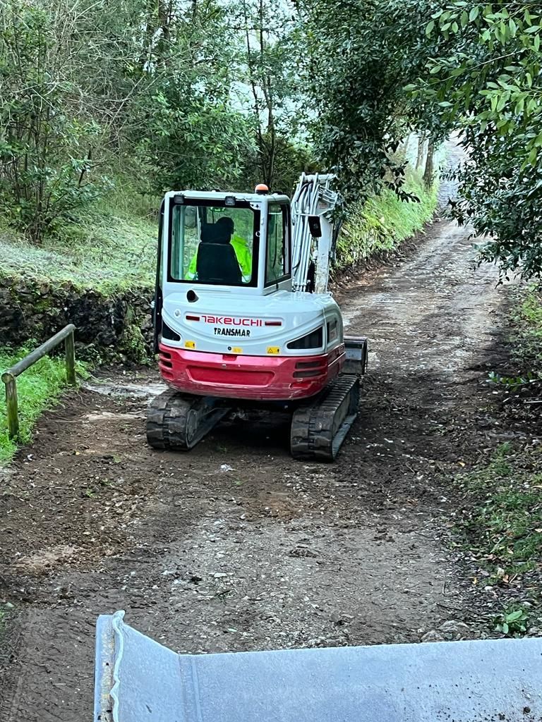 Una pequeña excavadora avanza por un camino de tierra.