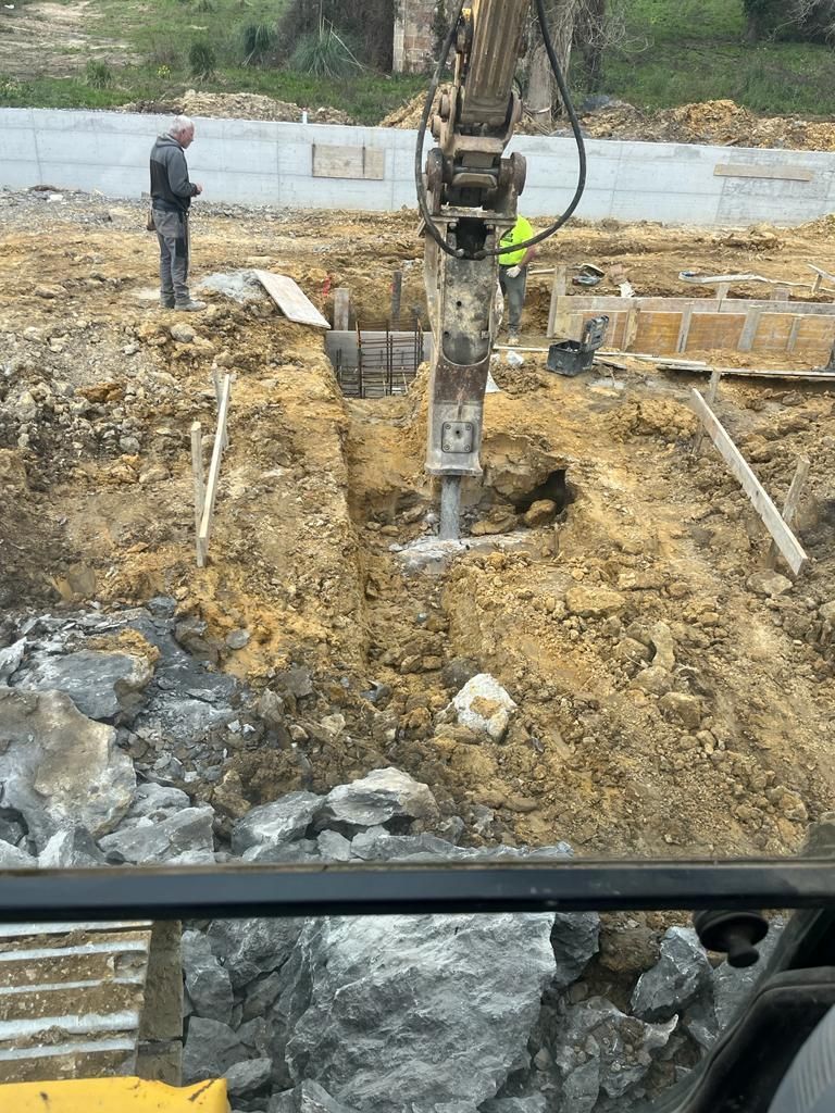 Un sitio de construcción con una excavadora y un martillo en la tierra.