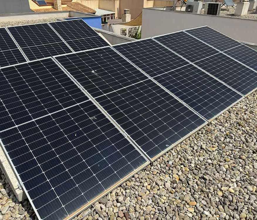 Paneles solares instalados en un tejado cubierto de grava, capturando la luz solar para generar energía.