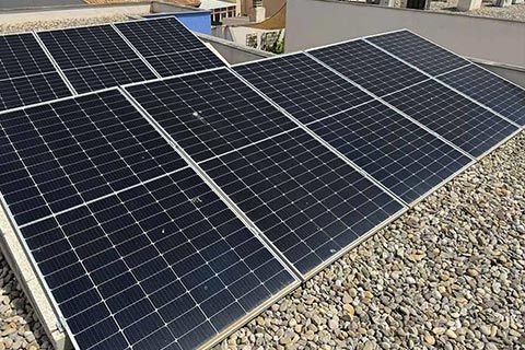 Paneles solares instalados en un techo de grava, orientados hacia la luz del sol.