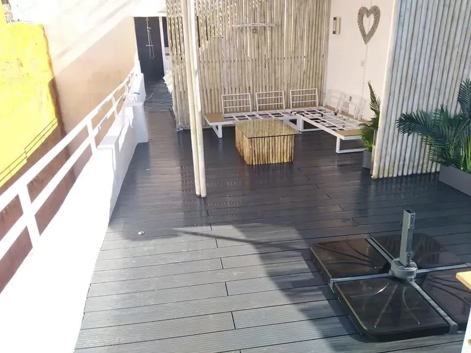 Patio exterior con suelo gris, asientos y una celosía decorativa de bambú.