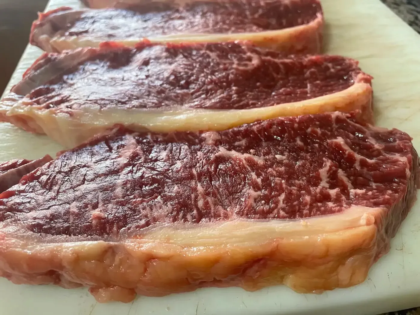 Guantes rosas, esponjas y una botella de spray sobre un fondo rosa.