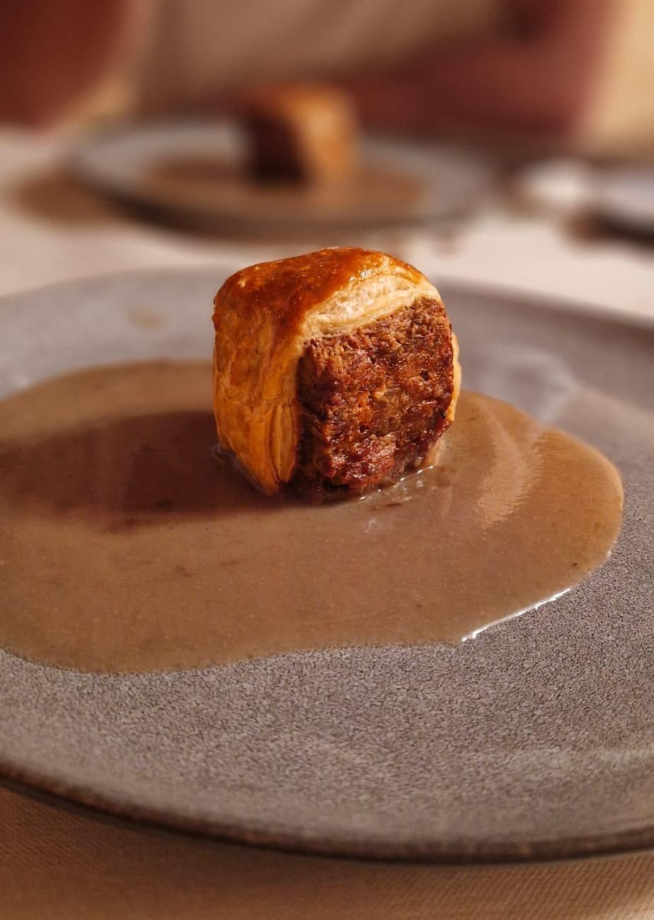 Tres croquetas doradas fritas en un plato, rociadas con una salsa de color claro.