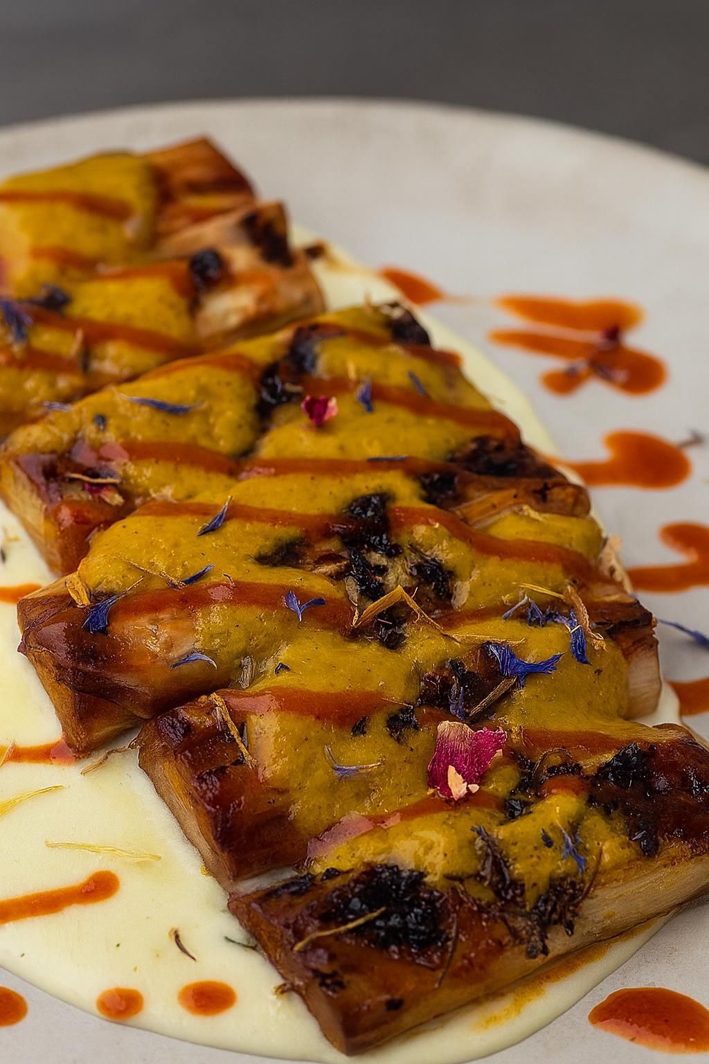 Pastel cuadrado con relleno de carne, servido en un charco de salsa marrón sobre un plato gris.