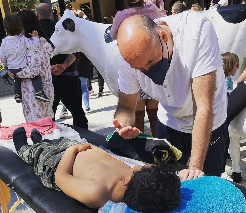Un hombre con una máscara está cepillando los dientes de un niño.