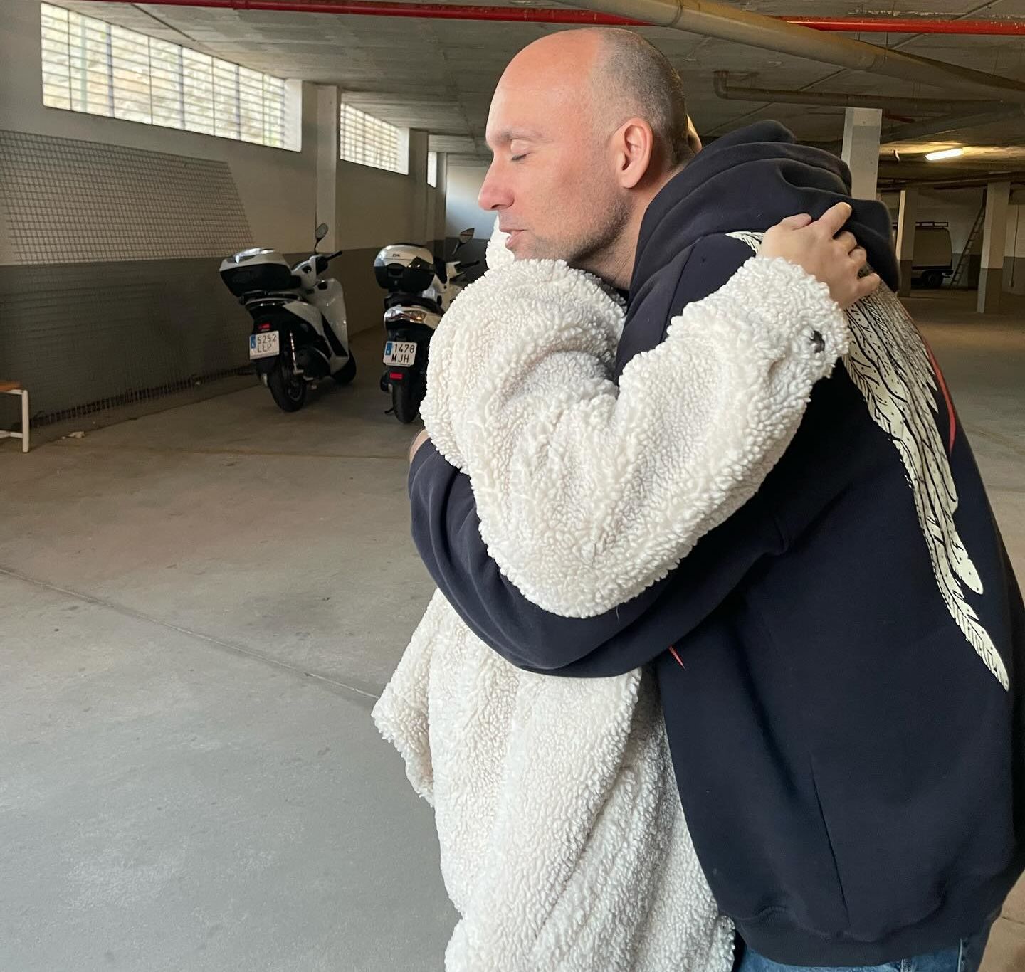 Un hombre abraza a una mujer en un estacionamiento.