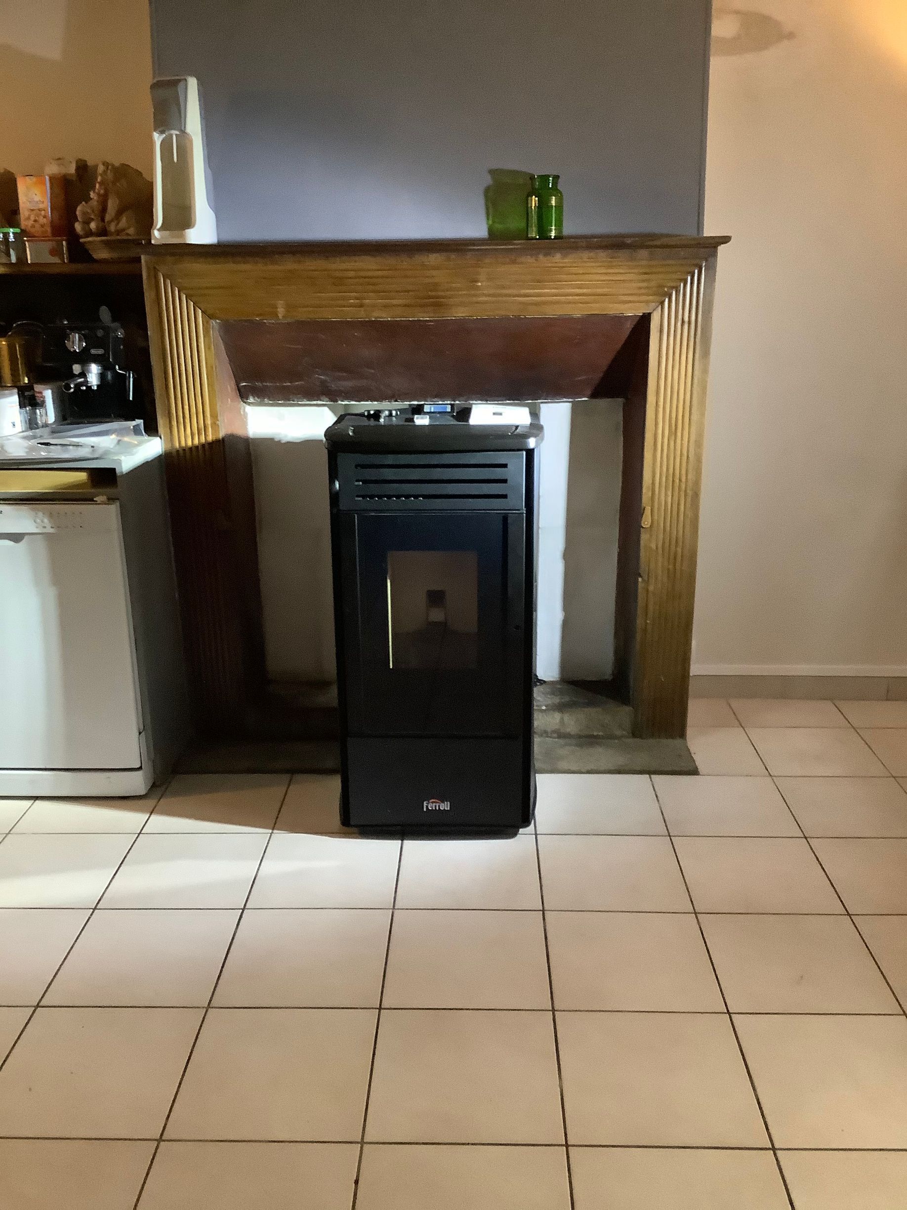 Un poêle à granulés noirs trône au centre d'un foyer de cheminée rustique en bois.