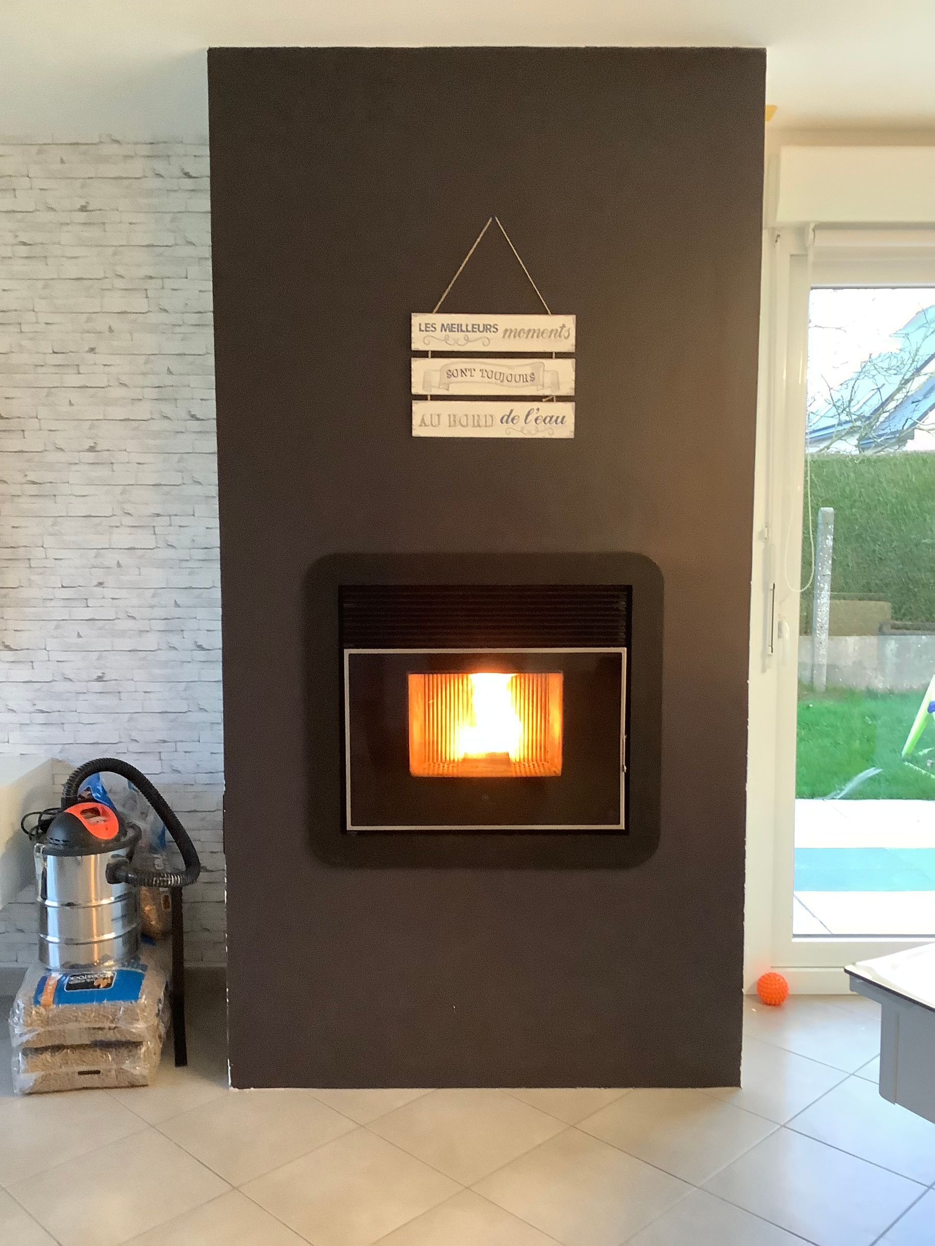 Un poêle à granulés encastré dans une cheminée sombre et texturée.