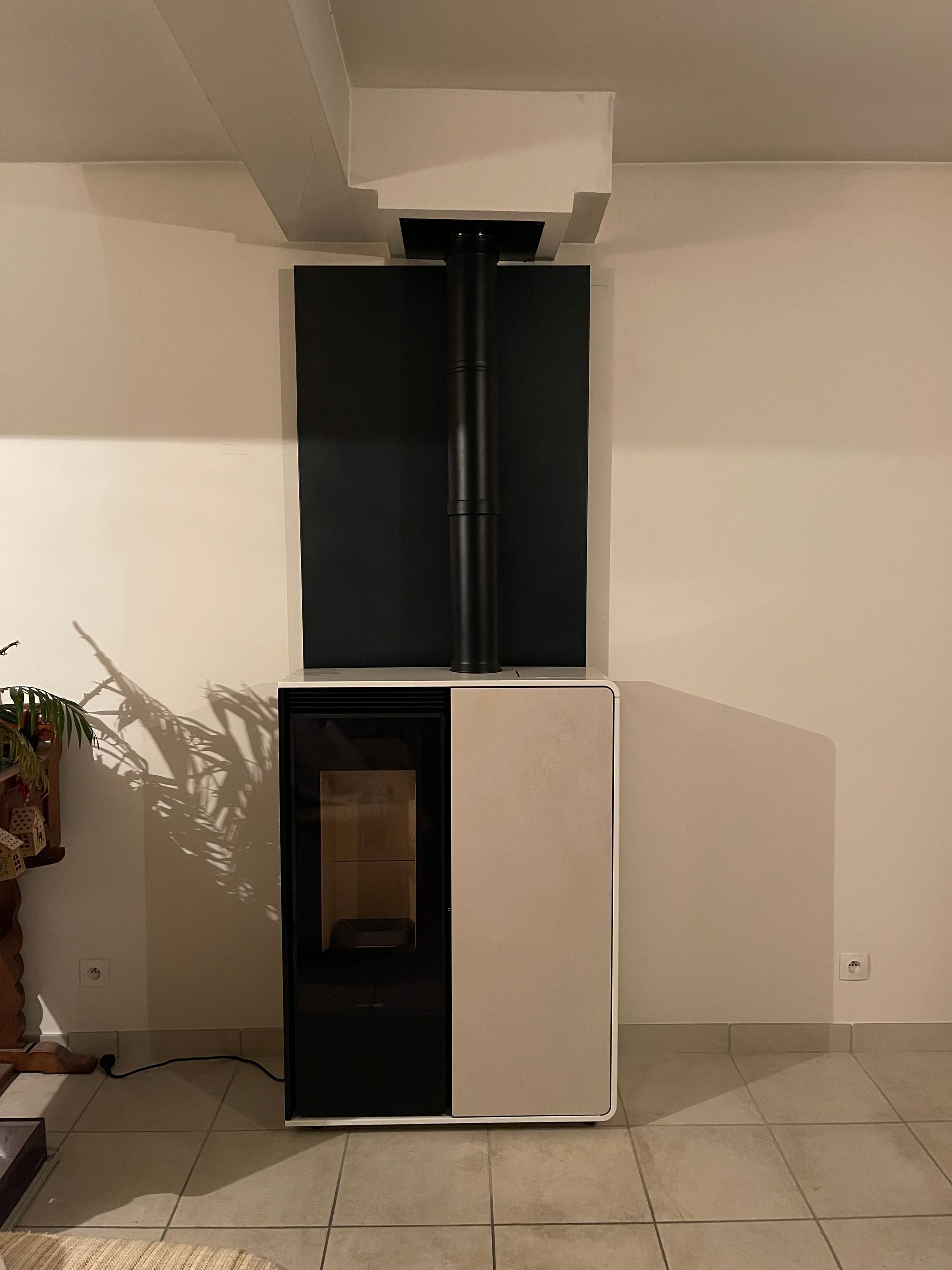 Un poêle à granulés moderne, avec une façade crème et des côtés noirs.