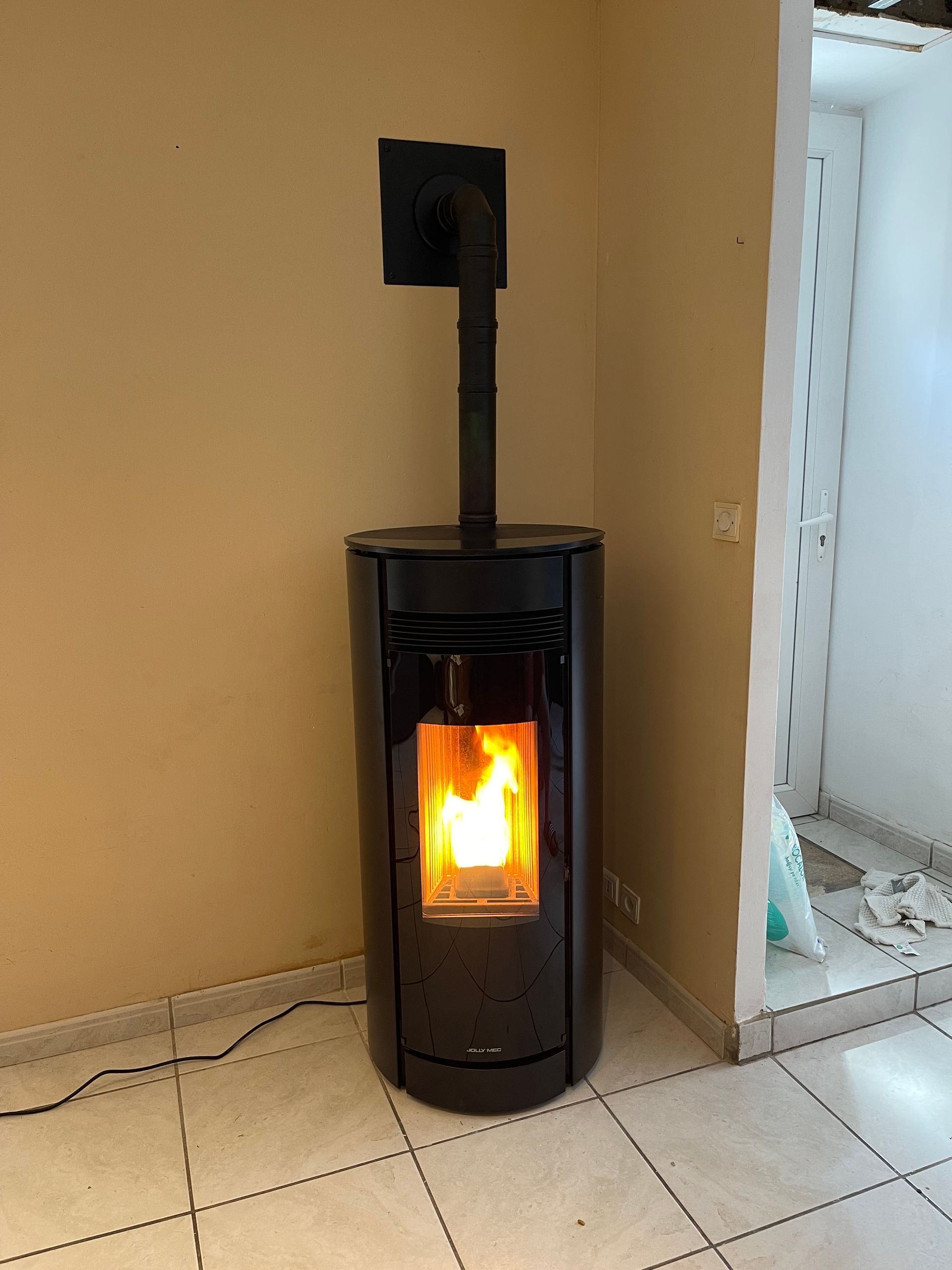 Dans une pièce, un poêle à granulés cylindrique noir.