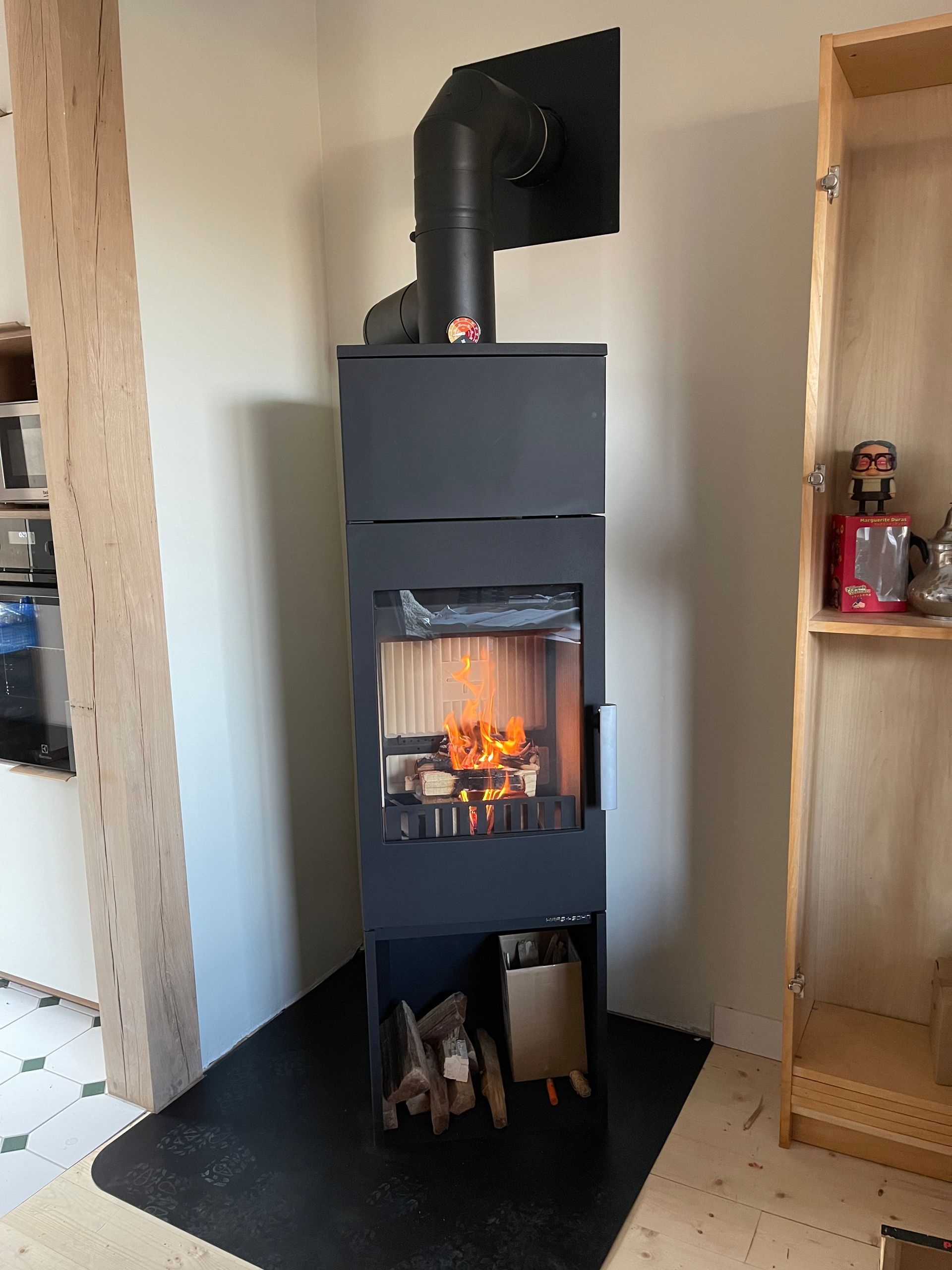 Un poêle à bois moderne, noir et imposant, avec un feu qui crépite.