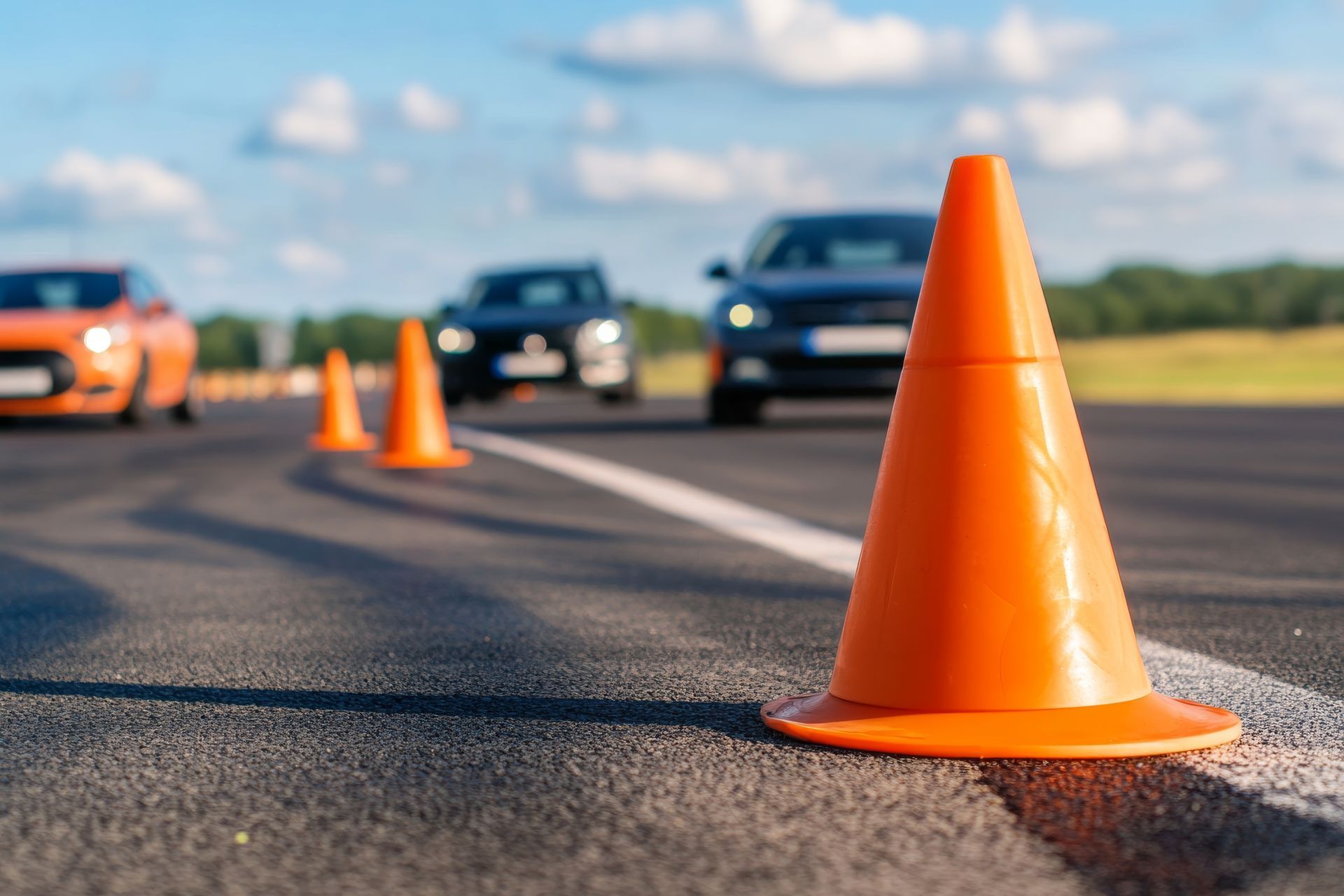 Cône de signalisation orange sur une route asphaltée avec des voitures en arrière-plan