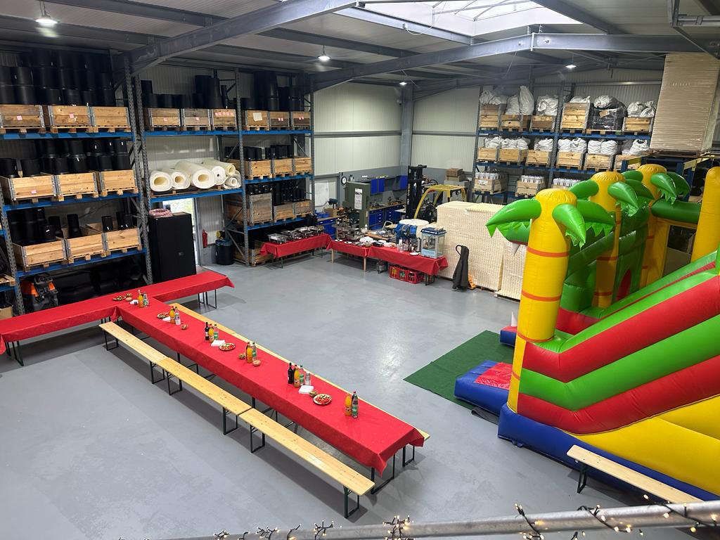 Firmenevent Indoor Hüpfburg und lange eingedeckte Tafel mit Bierzeltgarnitur
