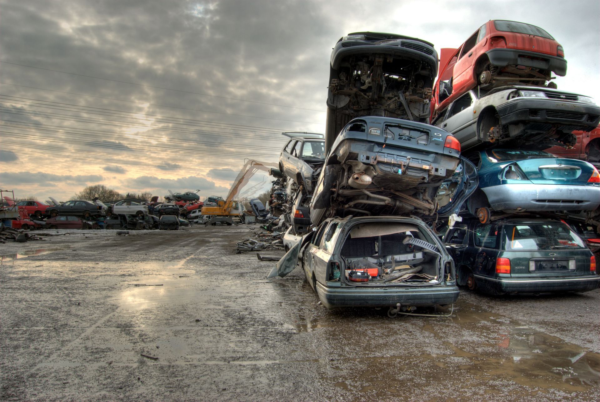 Tas de véhicules rouges et blancs écrasés, dans une décharge automobile.