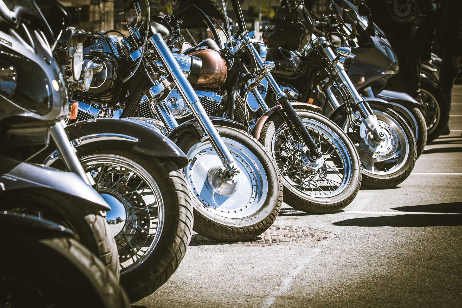 Rangée de motos custom garées sur un parking en pleine journée.