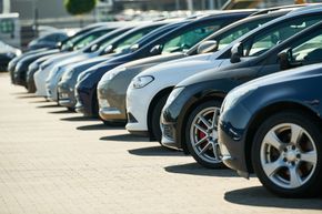 Rangée de voitures stationnées sur un parking en extérieur.