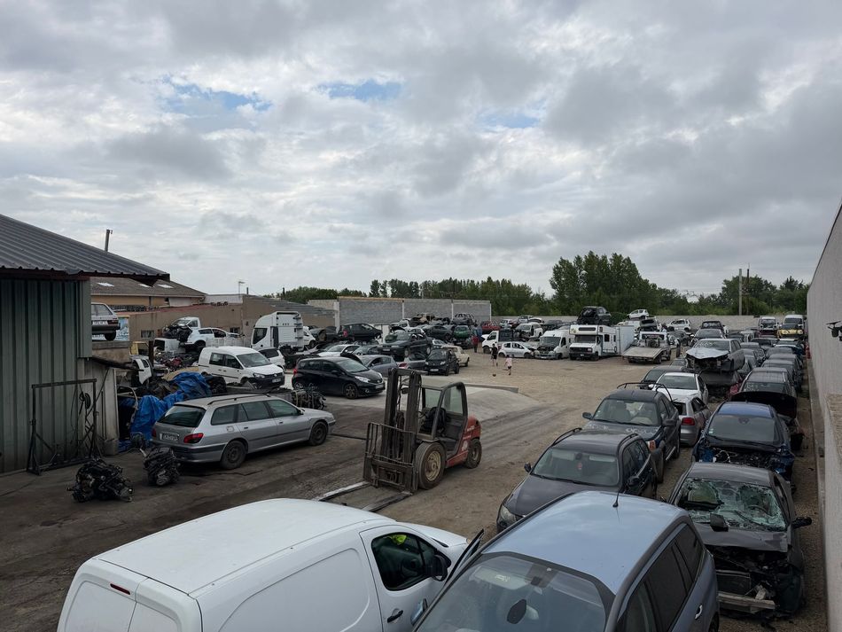 Casse automobile avec voitures accidentées et démontées sur un terrain vague.