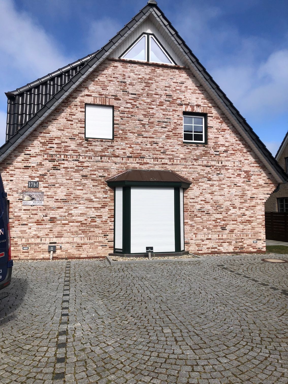 Ein Backsteinhaus mit einem weißen Garagentor und einem davor geparkten blauen Lieferwagen