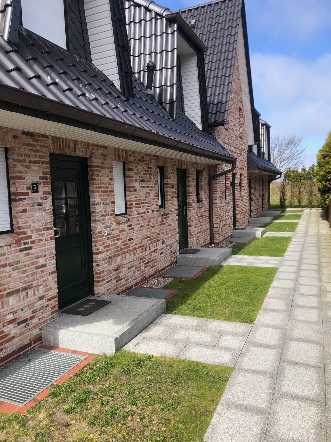 Eine Reihe von Backsteinhäusern, zu denen ein Gehweg führt.