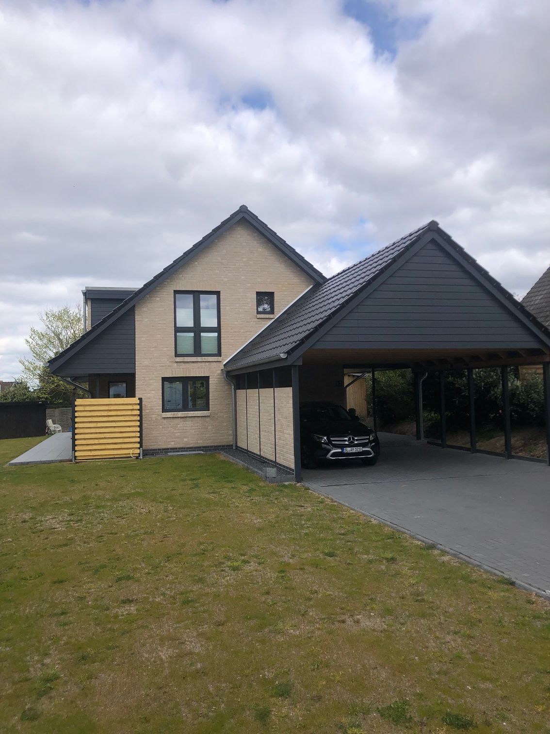 Ein Auto ist unter einem Carport vor einem Haus geparkt.
