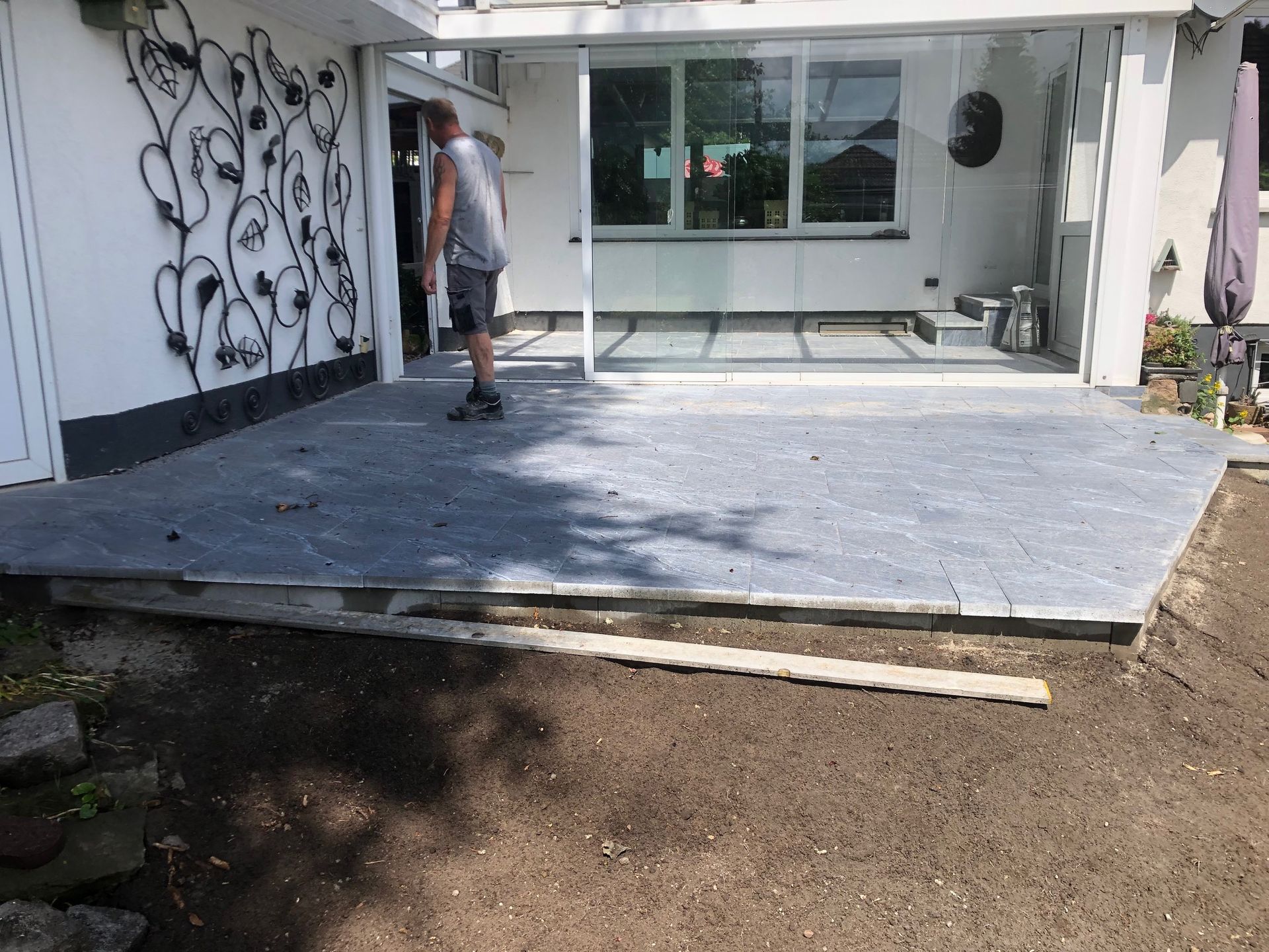 Ein Mann steht auf einer Terrasse vor einem Haus.