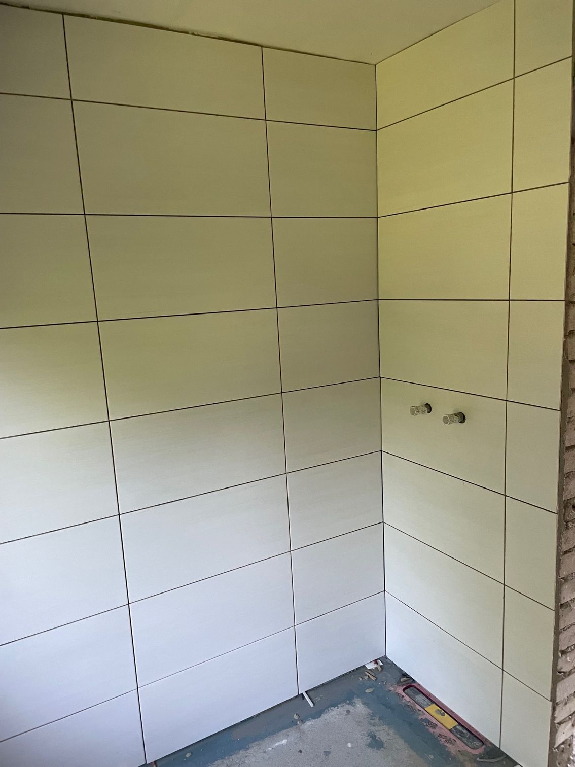 Ein Badezimmer mit weißen Fliesen an den Wänden und auf dem Boden.