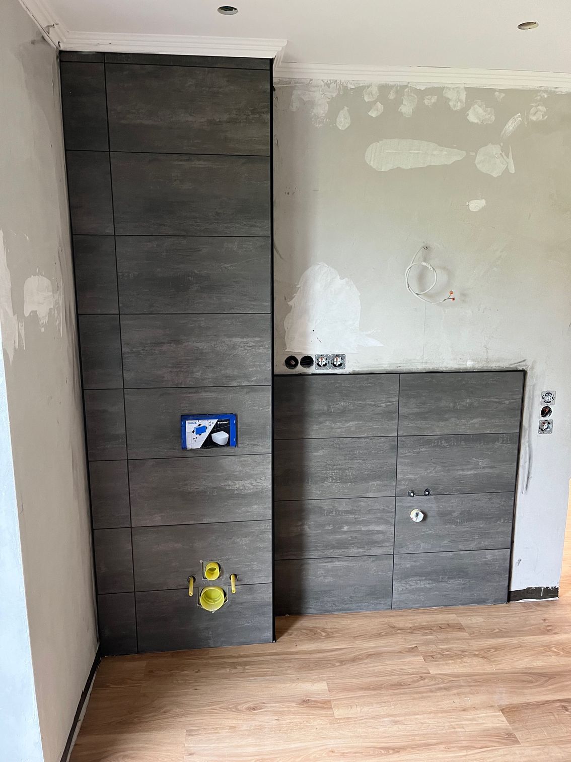 Ein Badezimmer mit gefliester Wand und Holzboden.