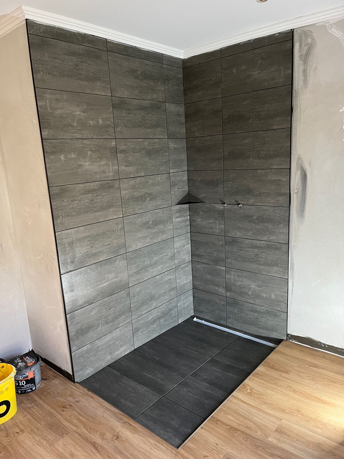 Ein Badezimmer mit gefliester Wand und ebenerdiger Dusche.