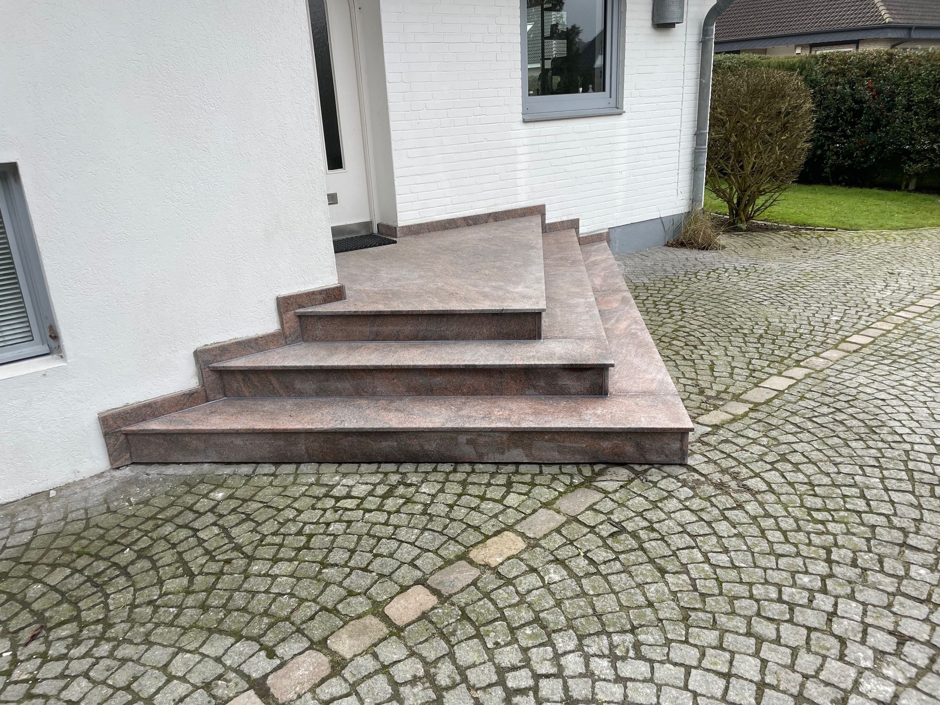 Eine Treppe führt zu einem Haus mit einer gepflasterten Auffahrt hinauf.