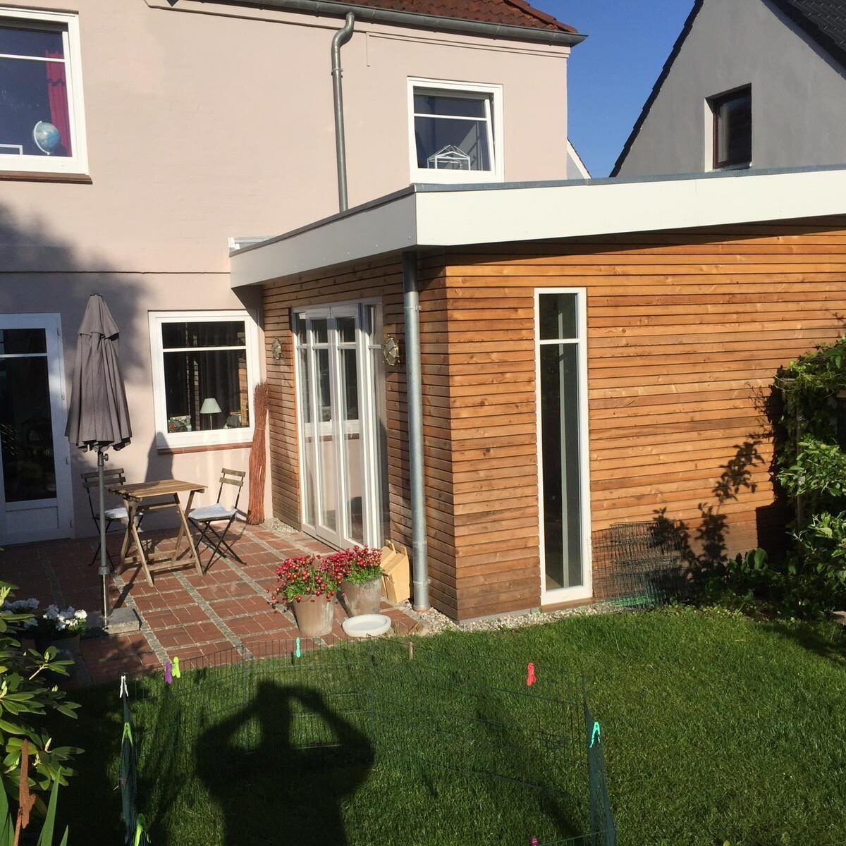 Ein Haus mit einem seitlichen Holzanbau