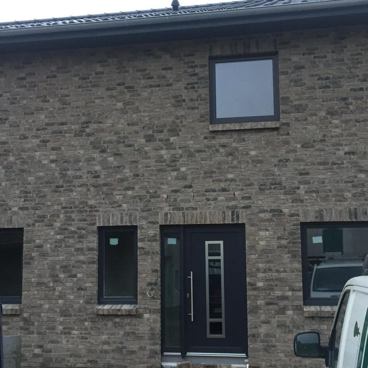 Ein Backsteinhaus mit einem davor geparkten Auto.