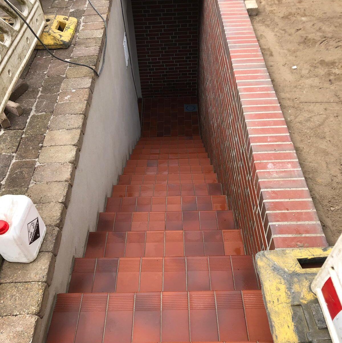 Eine Treppe, die zu einer Backsteinmauer hinaufführt.