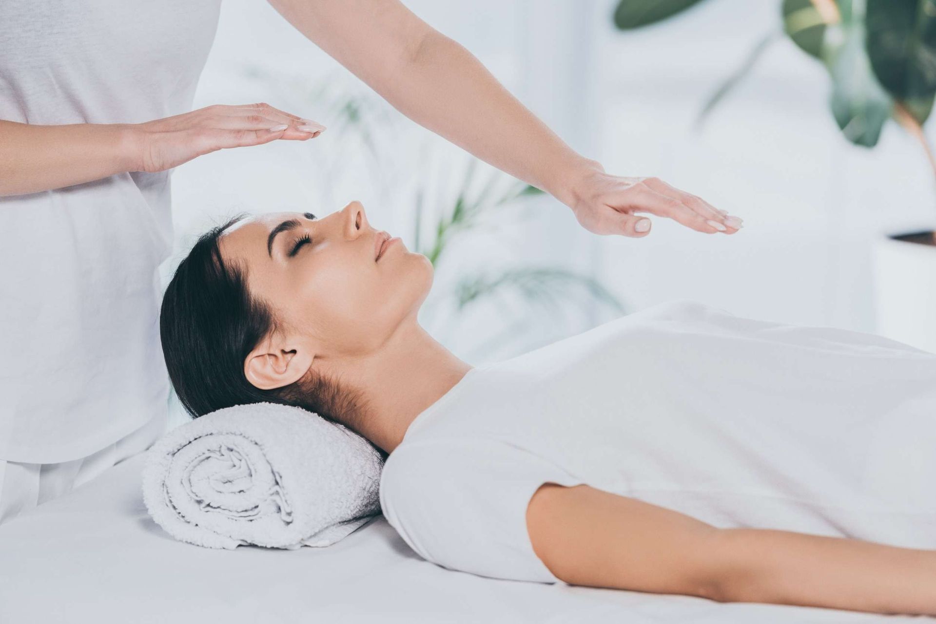 Mujer recibiendo Reiki con las manos sobre la cabeza, en el interior.